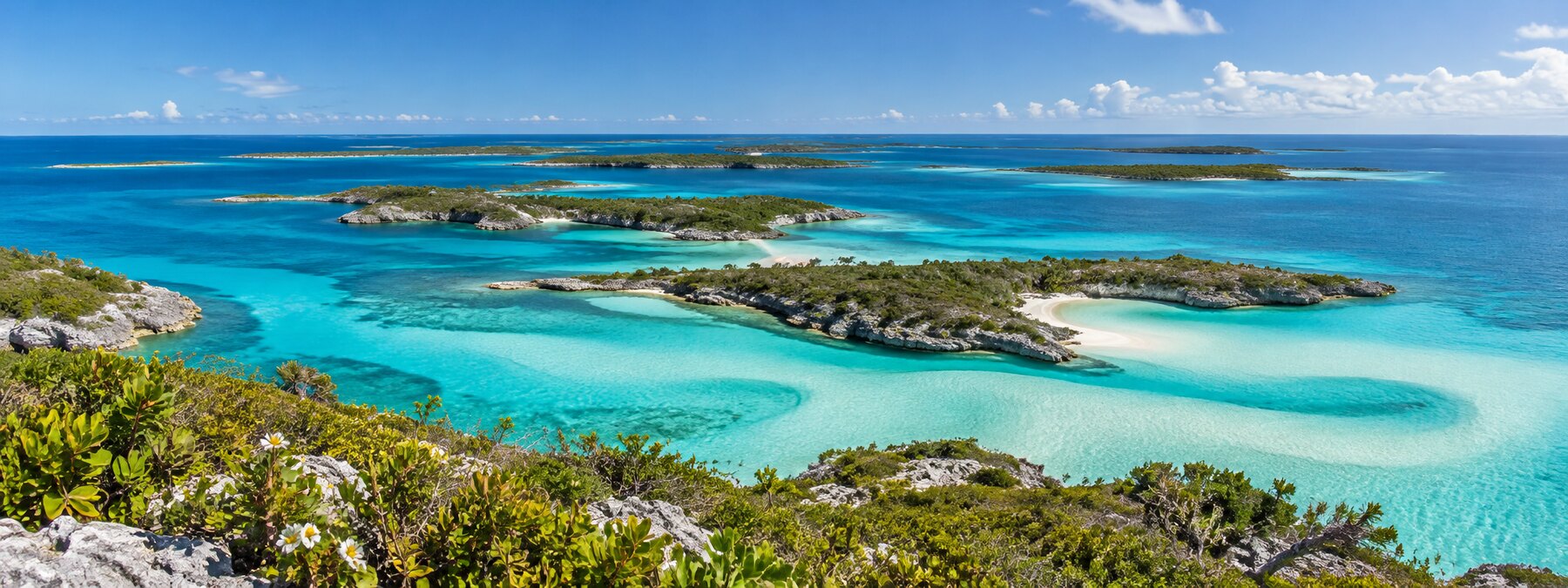 A wide aerial view of islands and clear turquoise water across The Bahamas