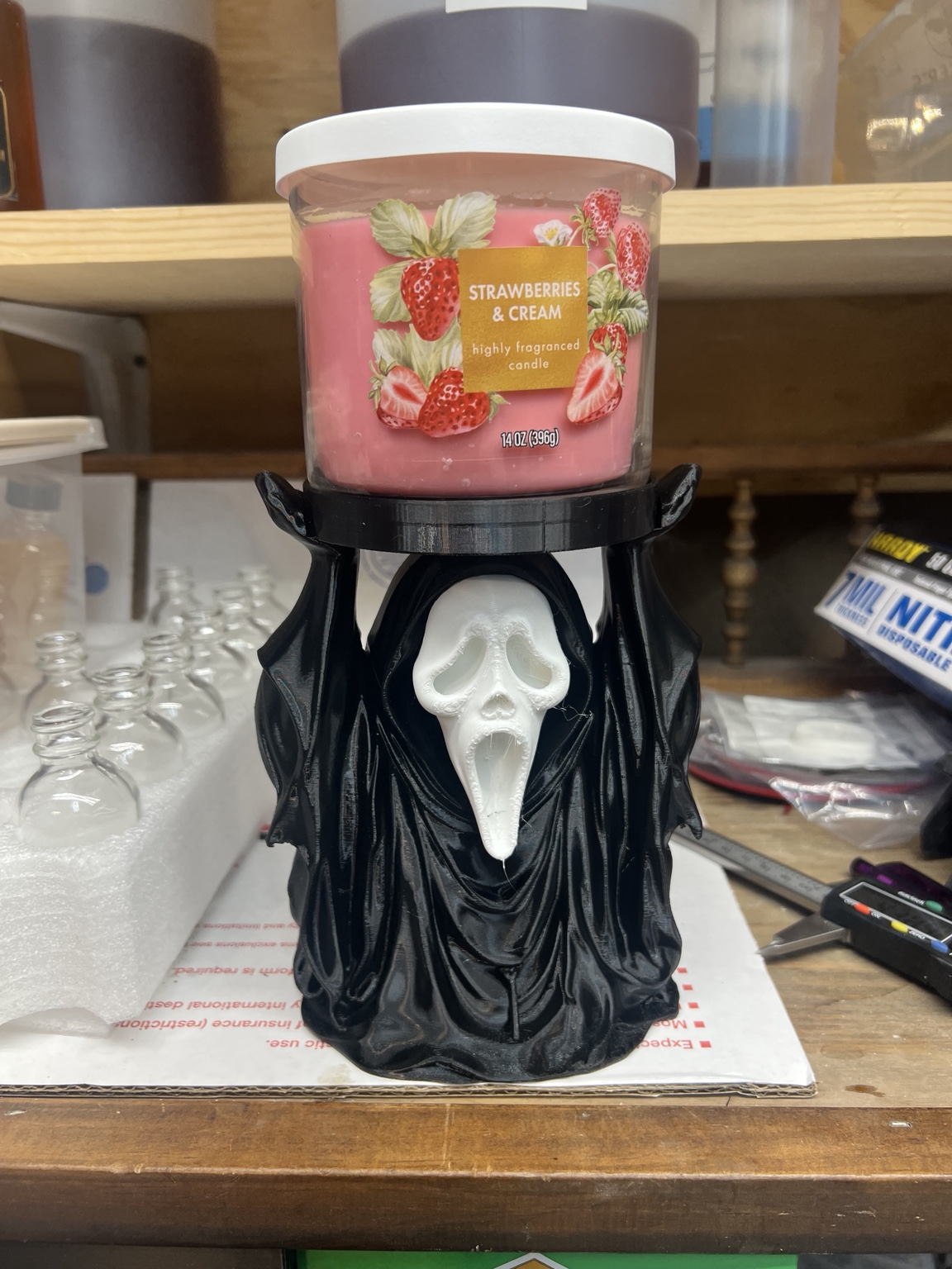 Scary movie inspired holder supporting a three wick candle